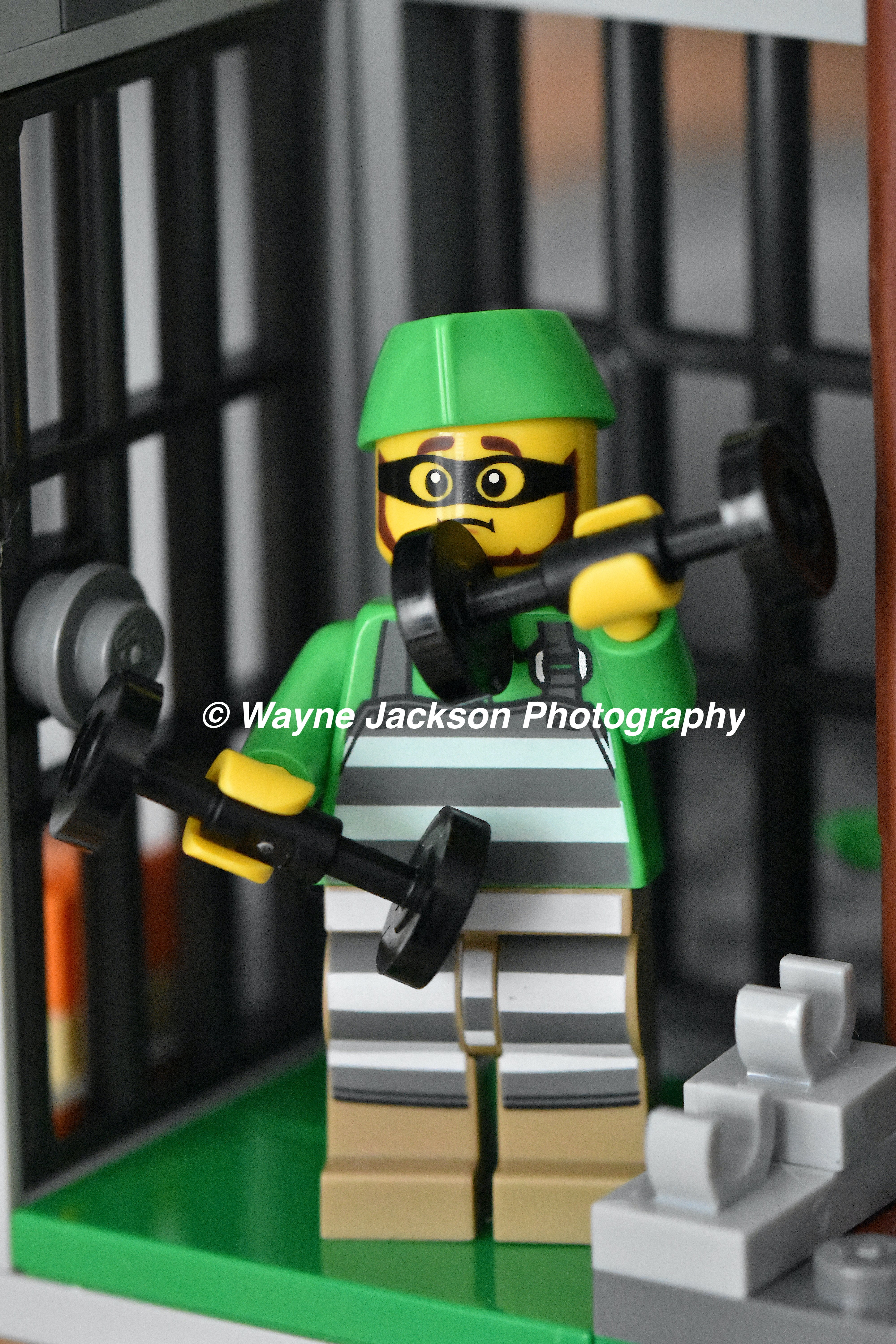 A Lego minifigure prisoner lifting dumbbells