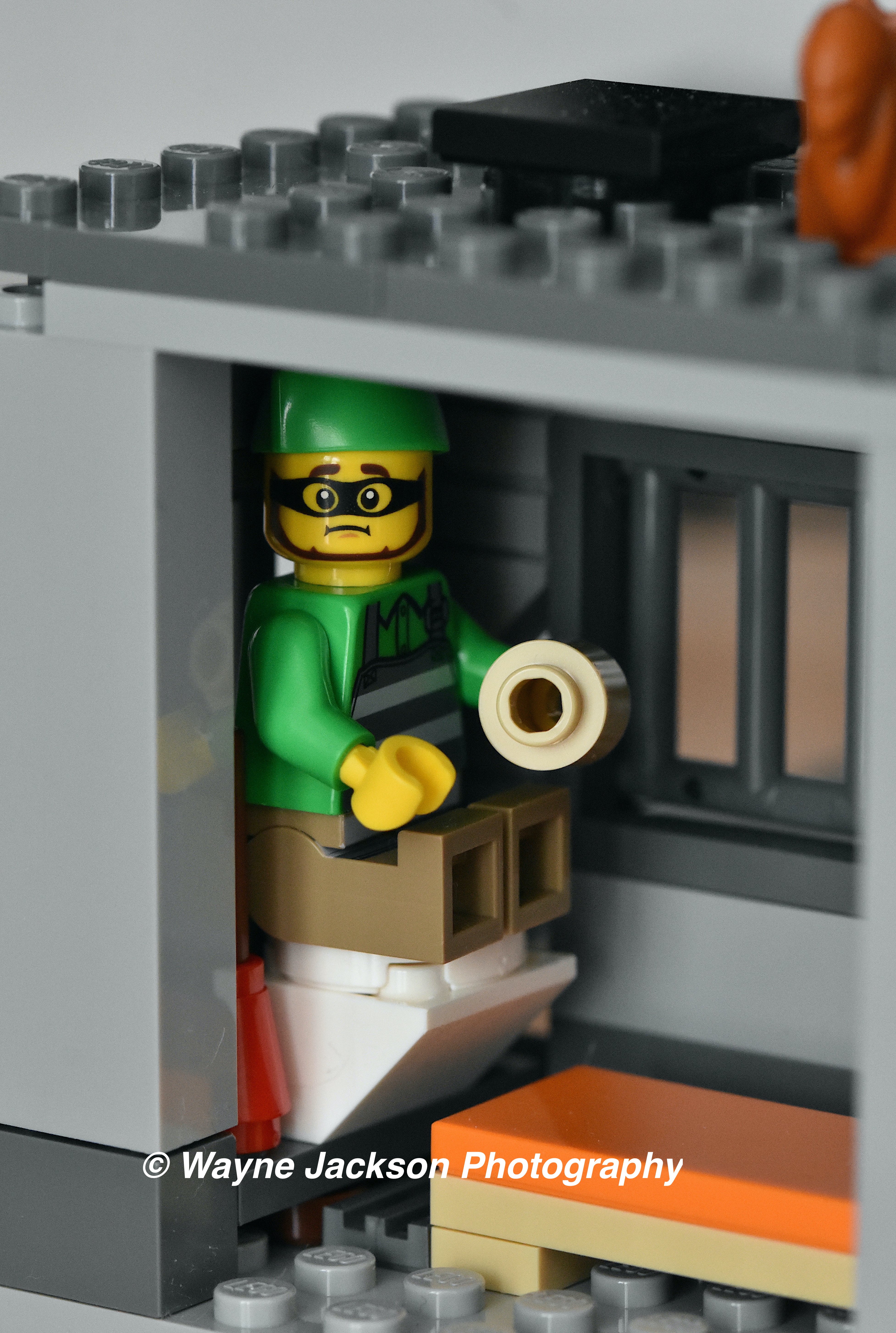 Lego minifigure prisoner on the toilet in his prison cell